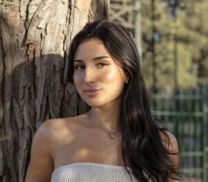 inner beauty and wellness A woman poses against a tree in outdoor natural light, showcasing elegance and beauty.