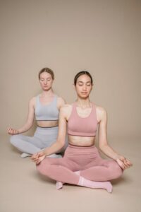 why some people look more attractive even without makeup Two women practicing yoga meditation in a minimalist studio, eyes closed, focusing on inner peace.