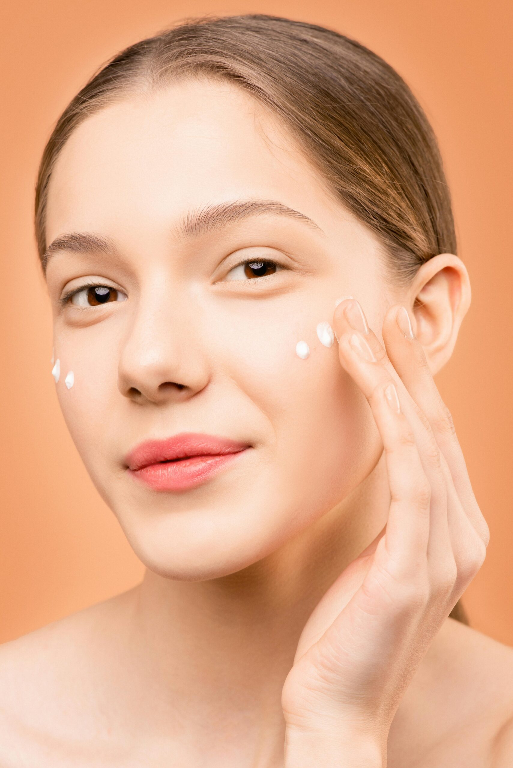 About Young woman applying facial cream for healthy skincare routine.